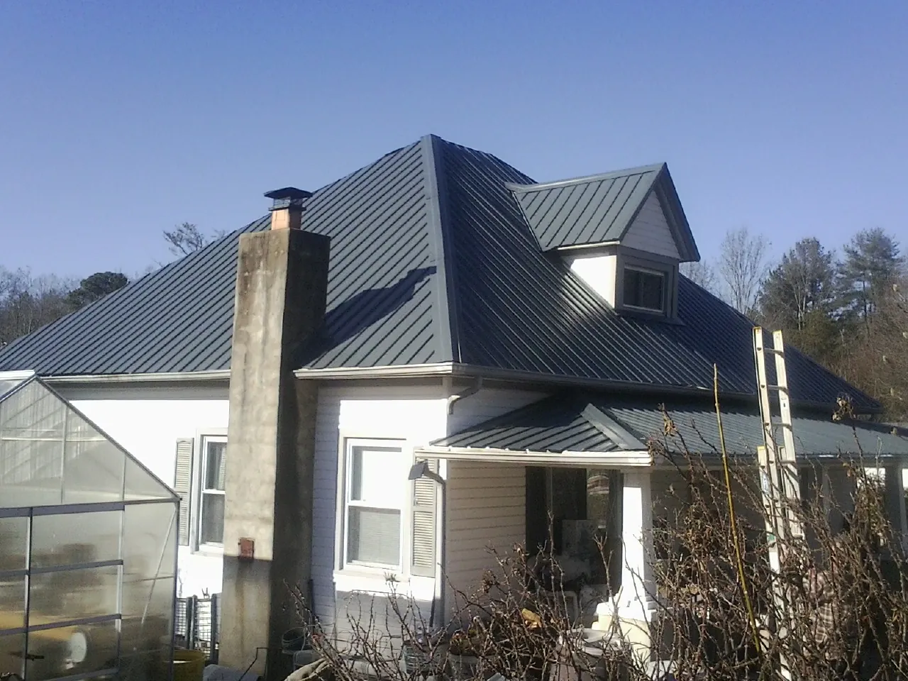 Dark blue standing seam metal roof on a white farmhouse with dormer — Slate & Tile Roof Repair by Roofing Brothers in Southwick