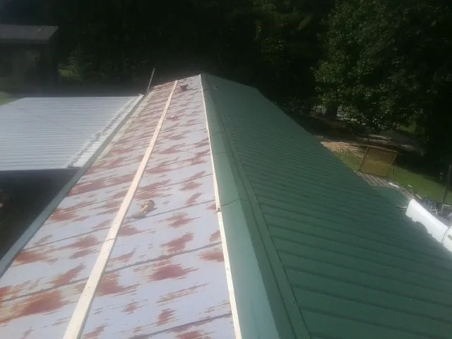 Old rusted panels beside newly installed green metal roofing — Wind Damage Roof Repair by Roofing Brothers in Southwick
