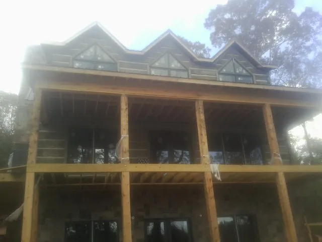 Dormers and porch framing on a large log home under construction — Roof Coating work by our crew in Southwick