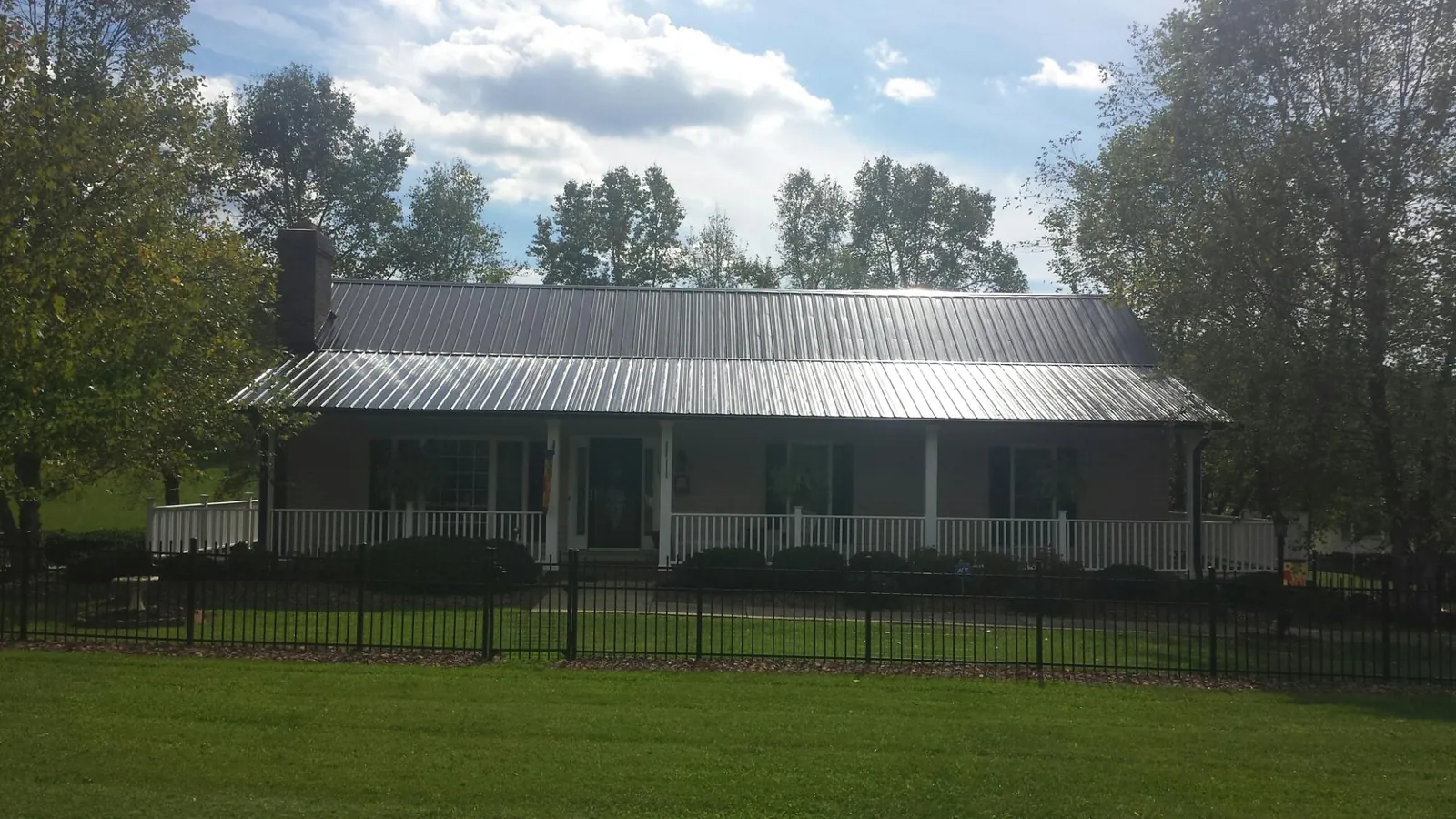 Gray metal roof on a brick ranch with a full width front porch — Gutter Guard Installation work by our crew in Southwick