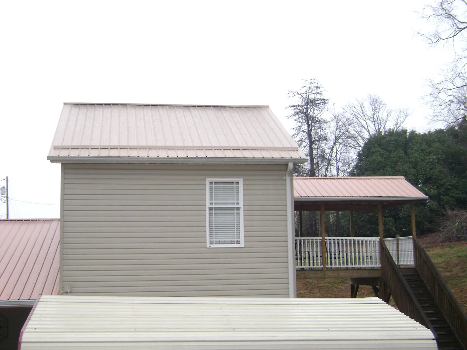 Tan metal roofs on a two story addition and attached porch, from a Roof Replacement job in Southwick
