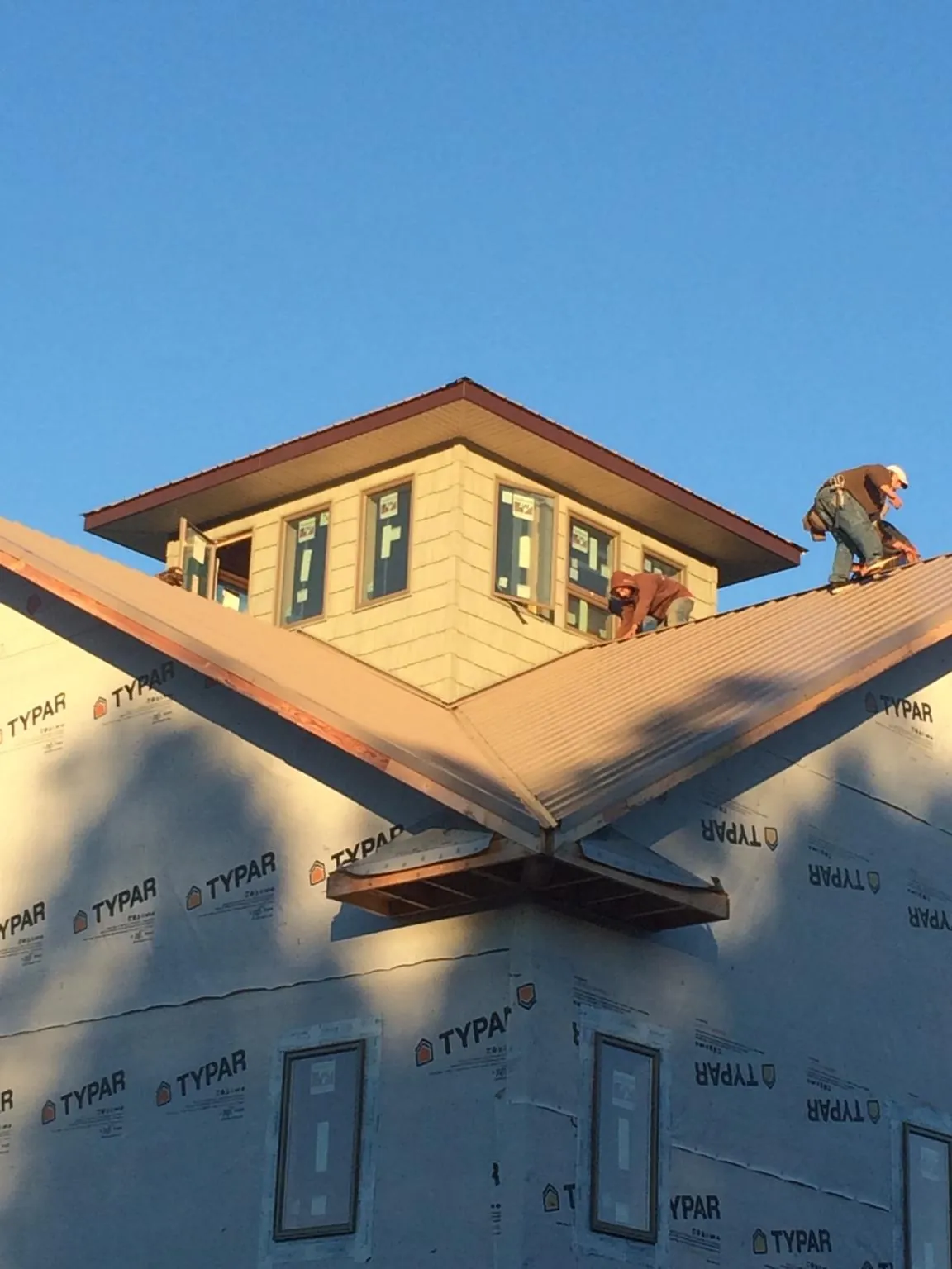 Roofers working around a rooftop cupola on a new metal roof at sunset — Roof Waterproofing in Southwick by Roofing Brothers